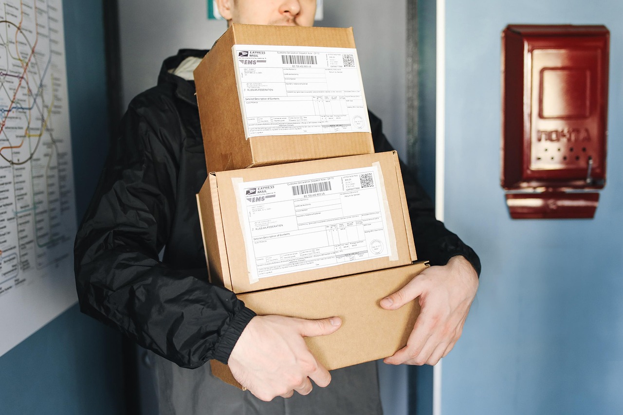 Caixas de papelão empilhadas e entregador preparando envio, representando a etapa de frete e logística ao configurar uma loja virtual