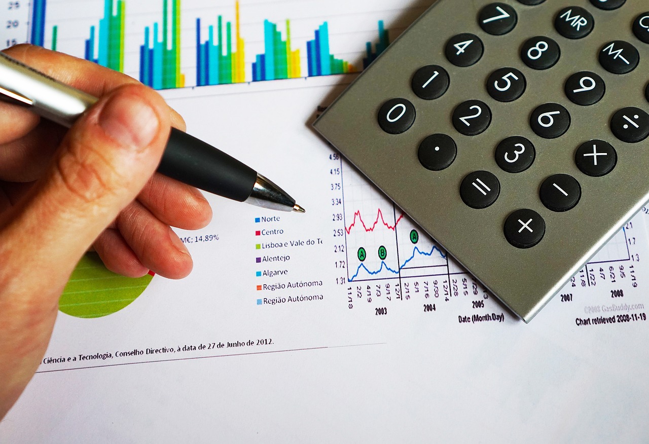 CPM marketing digital: mesa de escritório com calculadora, caneta e gráficos financeiros para calcular o custo por mil impressões